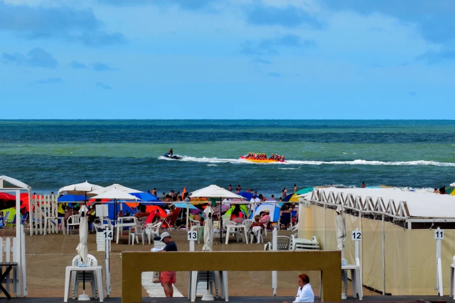 Playa Las Toscas en enero de 2025: carpas, sombrillas, personas y el mar en planos sucesivos. Fotografía de Ezarate.