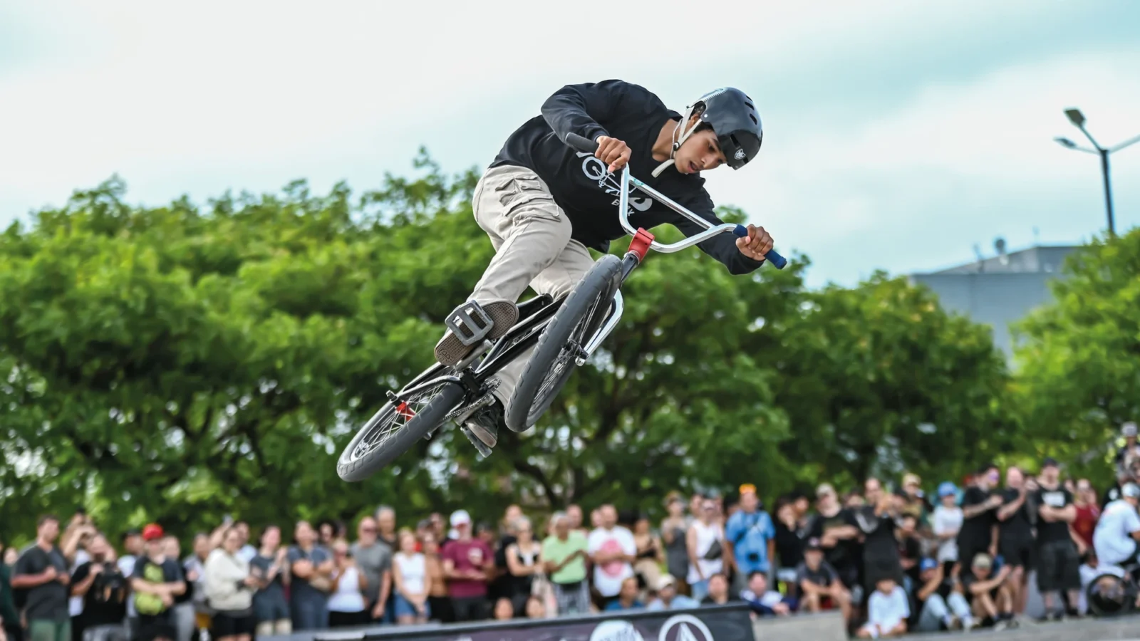 Una persona realiza un salto en BMX ante público y árboles. Fotografía de archivo difundida por GCBA.